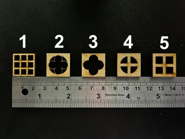 Ten MDF Embellishment blocks, each shaped like a square window for fairy or doll houses, are aligned above a 20 cm stainless steel ruler on a black surface. The ruler measures in centimeters from 0 to 20.